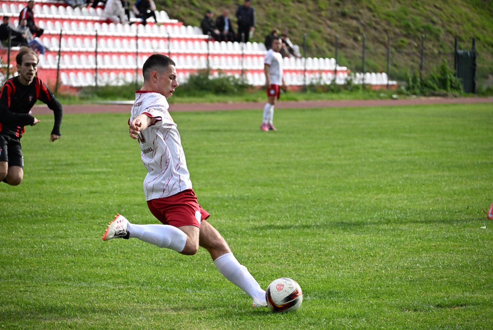 Играч во бело ја удира топката пред трибината
